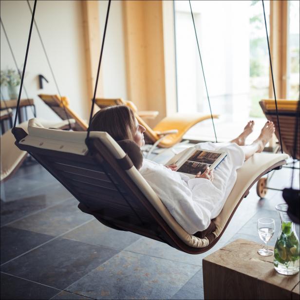 Eine Frau liest in einem Spa-Raum entspannt in einer Hängeliege.