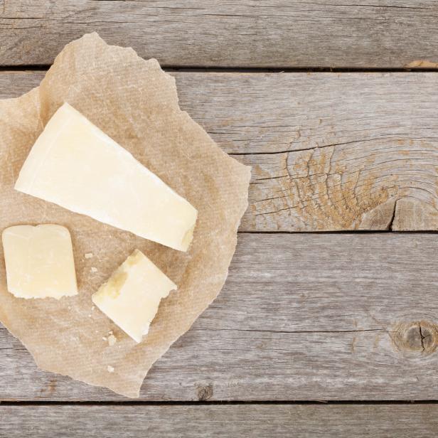 Parmesan liegt auf einem Stück Papier auf einem Holztisch.