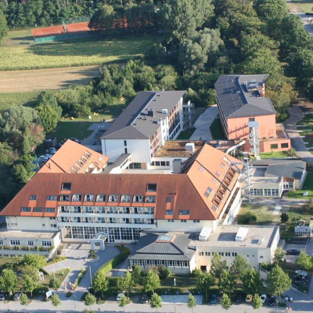 Luftaufnahme eines großen Hotelkomplexes mit umliegenden Feldern und Bäumen.
