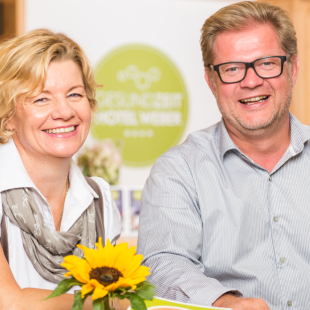 Petra und Alfred Weber lächeln in der Rezeption ihres Hotels.