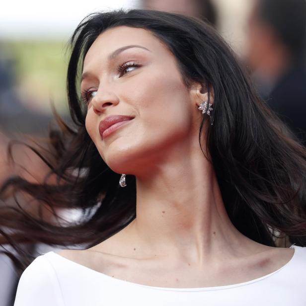Bella Hadid auf dem roten Teppich mit einem weißen Kleid und auffälligem Ohrschmuck.