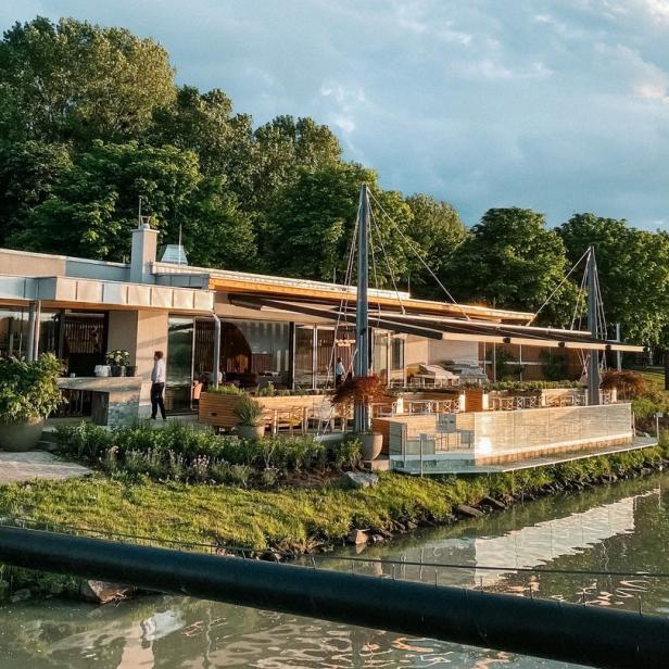 Ein modernes Gebäude mit Terrasse am Ufer eines Flusses.