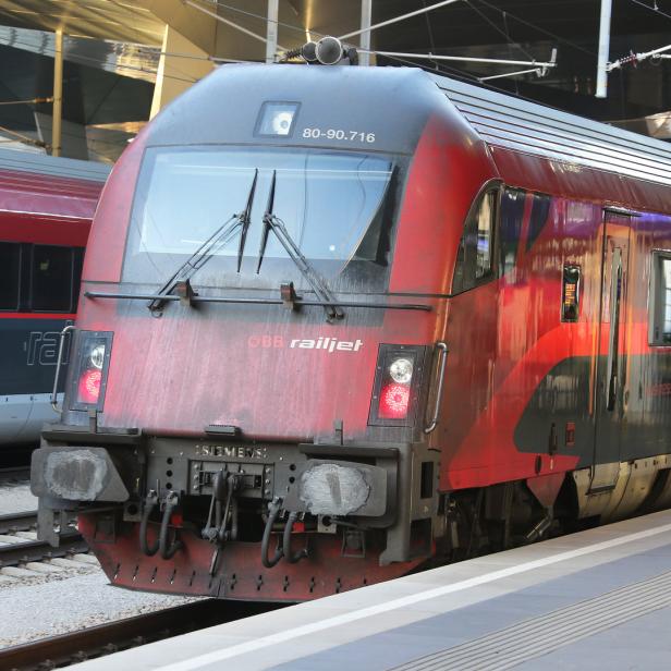 Ein roter ÖBB Railjet-Zug steht am Bahnsteig.