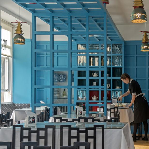 Eine Kellnerin bereitet in einem blau dekorierten Restaurant Speisen vor.