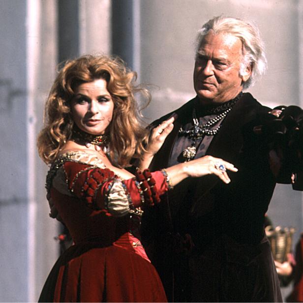 Ein Mann und eine Frau in Renaissance-Kostümen posieren vor einem Gebäude.