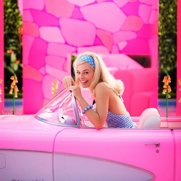 Margot Robbie als Barbie in einem pinkfarbenen Chevrolet Corvette Cabriolet.