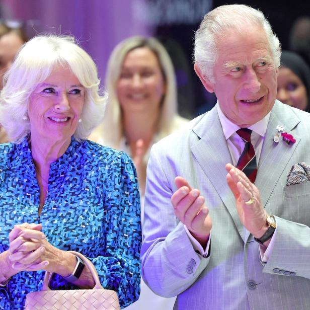 König Charles und Königin Camilla bei einer Veranstaltung, beide lächelnd und applaudierend.
