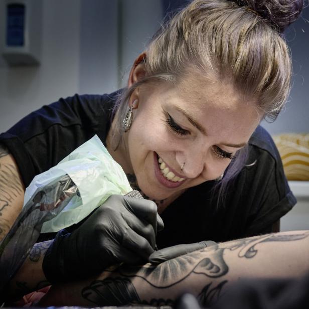 Stefanie Keuschnigg vom Dunkelbunt Tattoo Studio tätowiert einen Kunden.