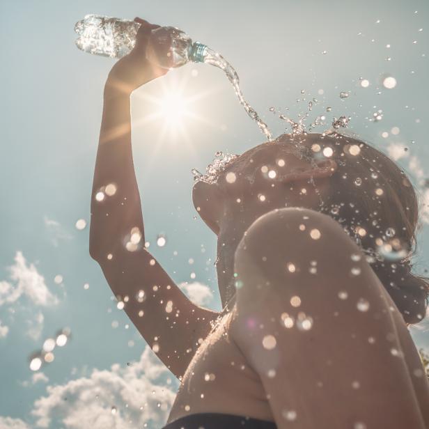 Eine Frau kühlt sich an einem heißen Sommertag mit Wasser ab.