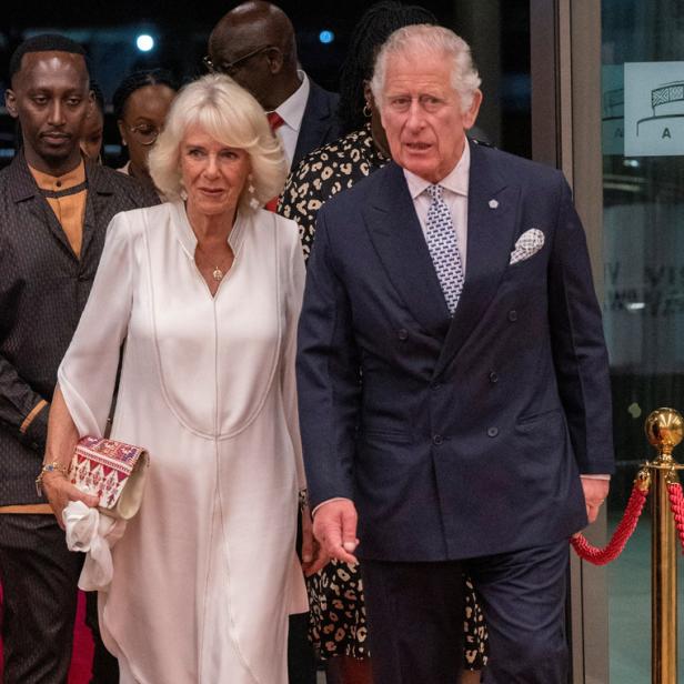 König Charles und Königin Camilla schreiten über einen roten Teppich.