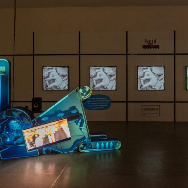 Eine Kunstinstallation mit Bildschirmen und blauer Beleuchtung in einem Ausstellungsraum.