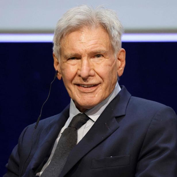 Harrison Ford trägt einen dunklen Anzug und ein Headset.