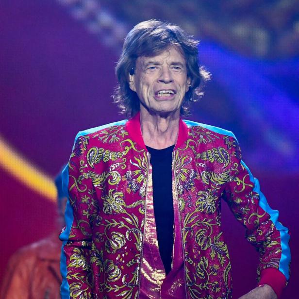 Mick Jagger tritt in einer bunten Jacke auf einer Bühne auf.