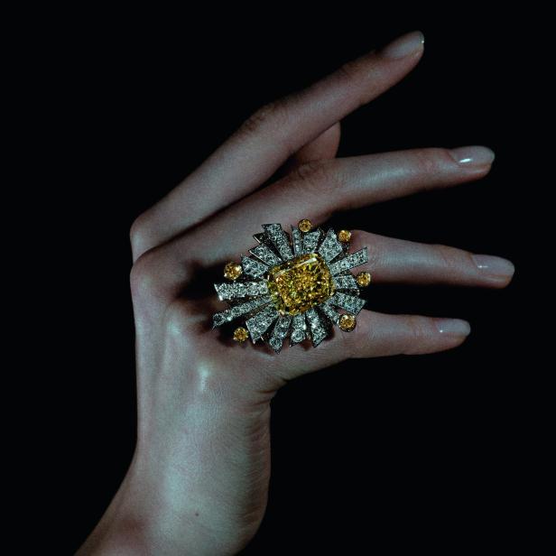 Die Hand einer Frau trägt einen auffälligen Ring mit gelbem Diamanten.