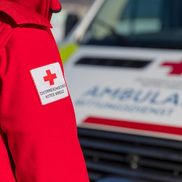 Ein Sanitäter in Rettungsjacke steht vor einem Rettungsfahrzeug.