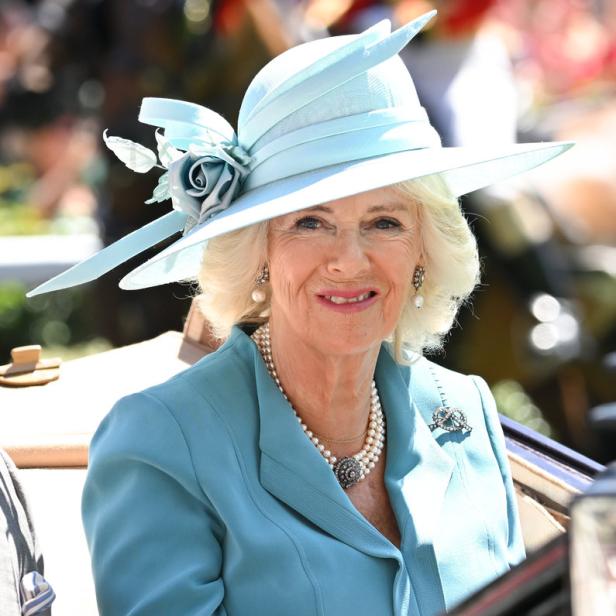 Königin Camilla trägt einen hellblauen Hut und eine passende Jacke.