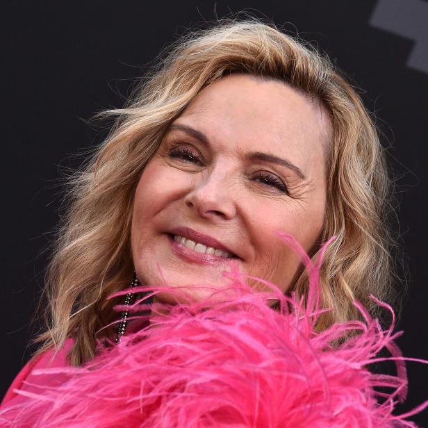 Kim Cattrall lächelt mit einer pinkfarbenen Federboa um den Hals.