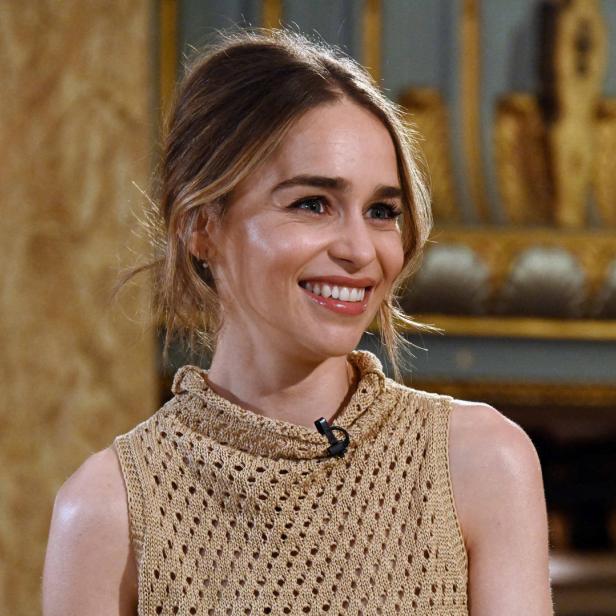 Emilia Clarke lächelt in einem ärmellosen, beigen Oberteil.