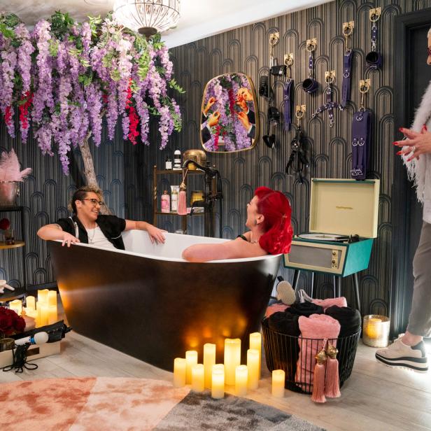 Zwei Personen entspannen in einer Badewanne, während eine dritte Person im Raum steht.