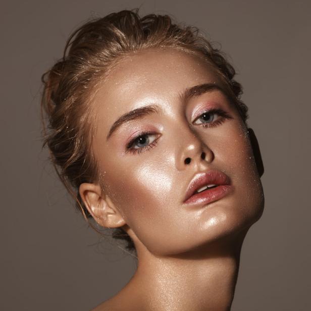 Porträt einer jungen Frau mit glänzendem Make-up und hochgesteckten Haaren.