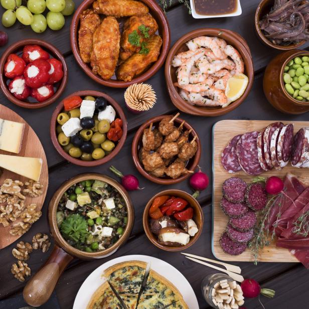 Eine Auswahl an Tapas, darunter Käse, Wurst, Oliven und gefüllte Paprika.