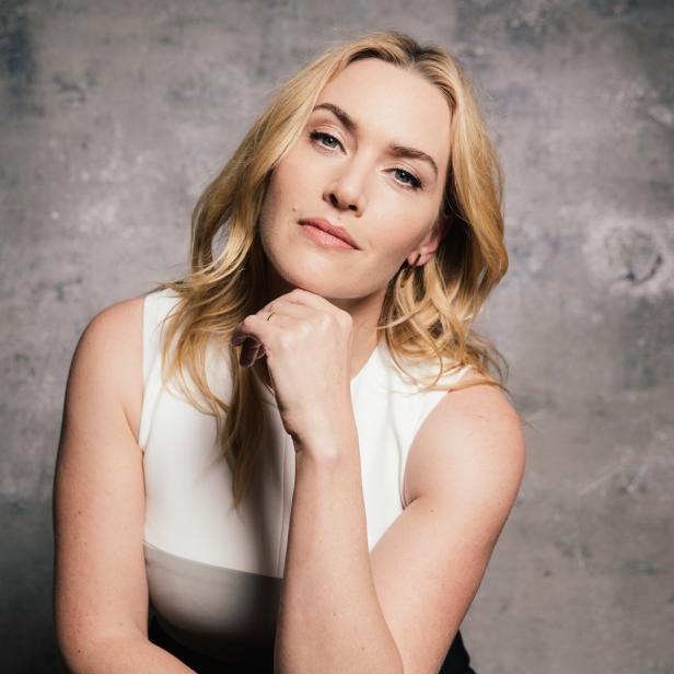 Kate Winslet posiert vor einer grauen Wand.