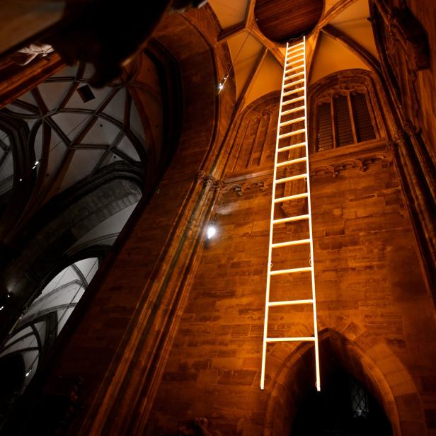 Eine leuchtende Leiter reicht in einer Kirche bis zur Decke.