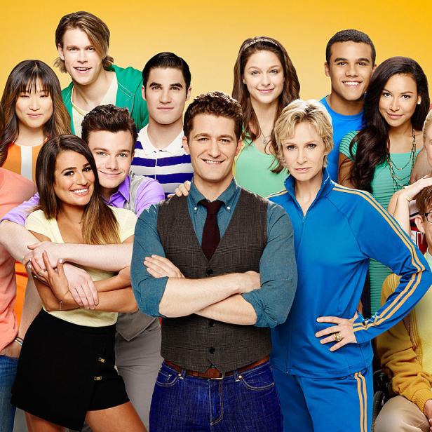Die Besetzung der Fernsehserie „Glee“ posiert vor einem gelben Hintergrund.