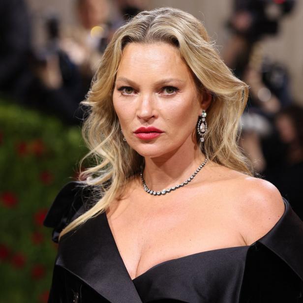 Kate Moss in einem schwarzen Kleid mit tiefem Ausschnitt und auffälligem Schmuck.