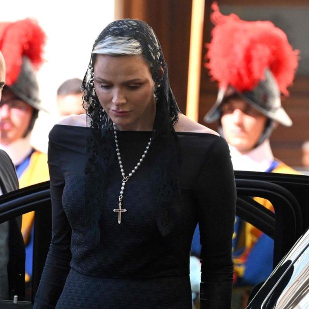Fürstin Charlène trägt ein schwarzes Kleid und eine Kopfbedeckung mit Schleier.
