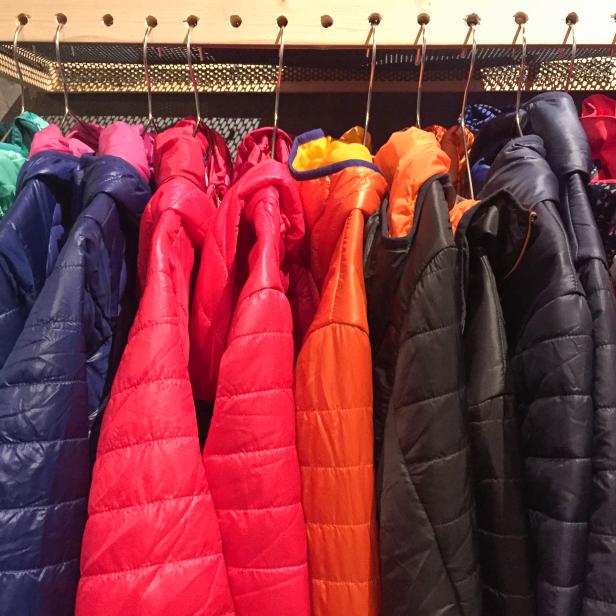 Bunte Winterdaunenjacken hängen an einer Kleiderstange.