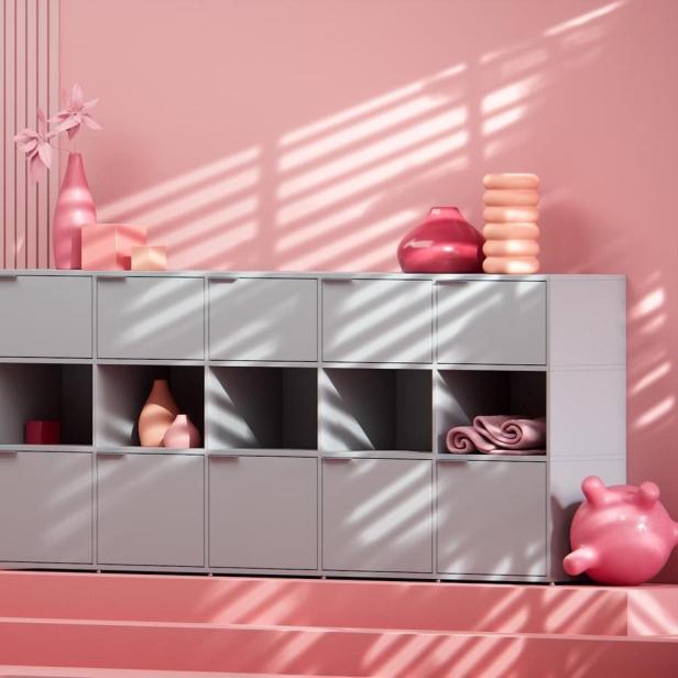 Ein graues Regal mit rosa Dekorationen steht vor einer rosa Wand.