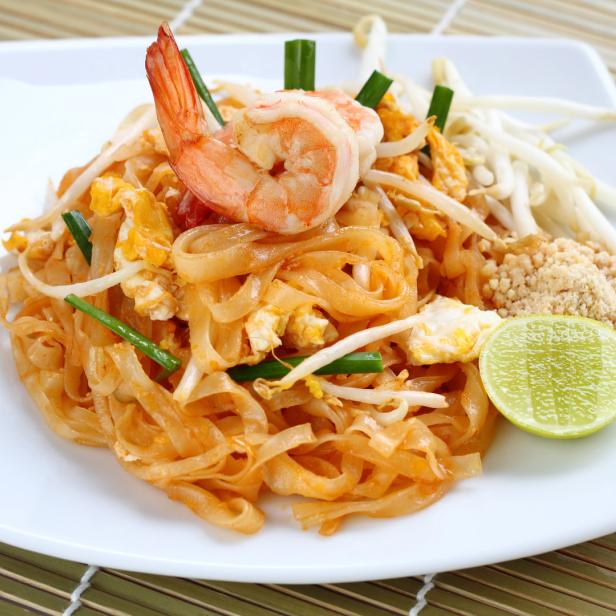 Ein Teller Pad Thai mit Garnelen, Sprossen, Limette und Erdnüssen.