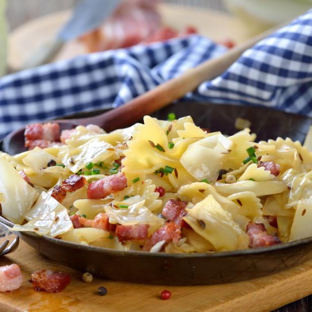 Eine Pfanne mit Krautwickel und Farfalle-Nudeln, garniert mit Schnittlauch.