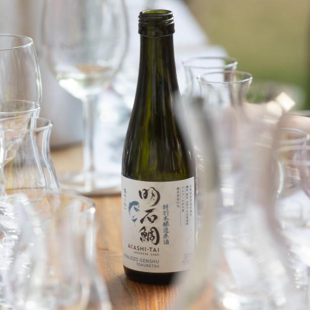 Eine Flasche Akashi-Tai Honjozo Genshu Sake steht auf einem Tisch mit Gläsern.