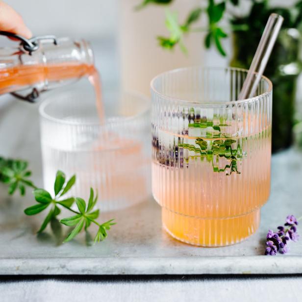 Ein Getränk wird in ein geripptes Glas mit Lavendel und einem Strohhalm gegossen.