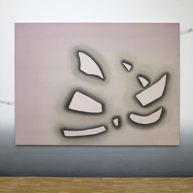 Ein abstraktes Gemälde mit rosa Hintergrund und weißen, fragmentartigen Formen hängt an einer Wand.