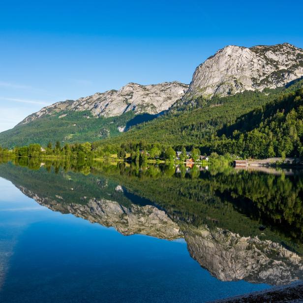 Der Altausseer See spiegelt die umliegenden Berge und den klaren blauen Himmel wider.