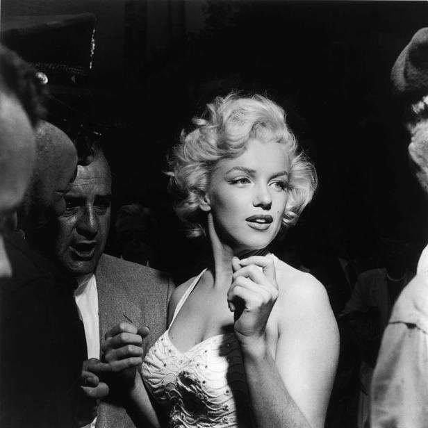 Marilyn Monroe umringt von Menschen bei einer Veranstaltung.