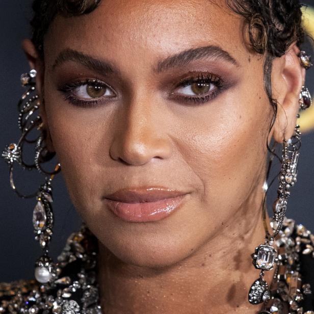 Nahaufnahme von Beyoncé mit aufwendigen Ohrringen und glänzendem Make-up.