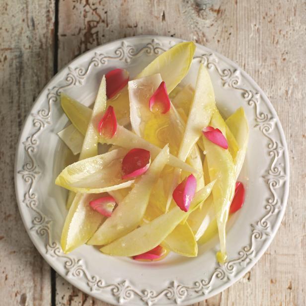 Ein Teller mit Endiviensalat, garniert mit Rosenblättern.