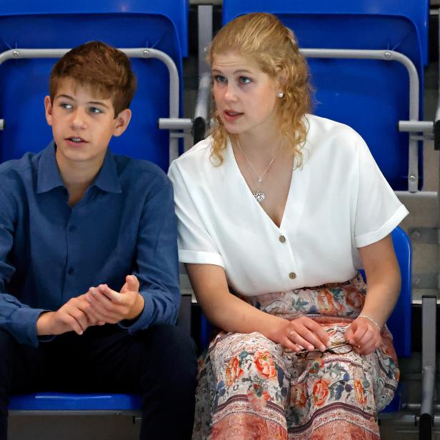 James, Viscount Severn, sitzt neben einer jungen Frau auf blauen Sitzen.