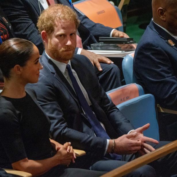 Prinz Harry und Meghan sitzen bei einer Veranstaltung in einem Publikum.