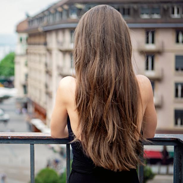 Eine Frau steht auf einem Balkon und blickt auf die Stadt.