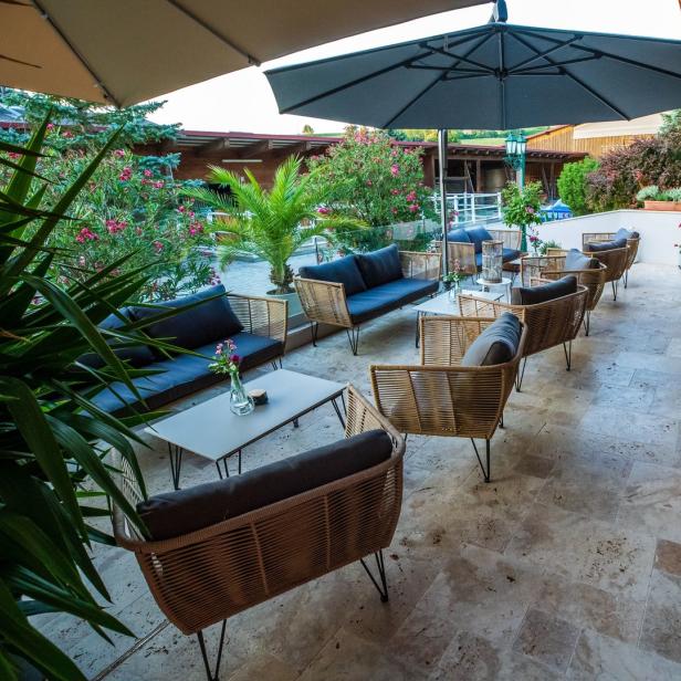 Einladende Terrasse mit Korbmöbeln und üppiger Bepflanzung.
