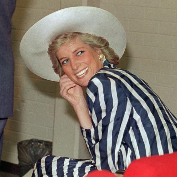 Prinzessin Diana lächelt mit einem gestreiften Blazer und einem Hut.