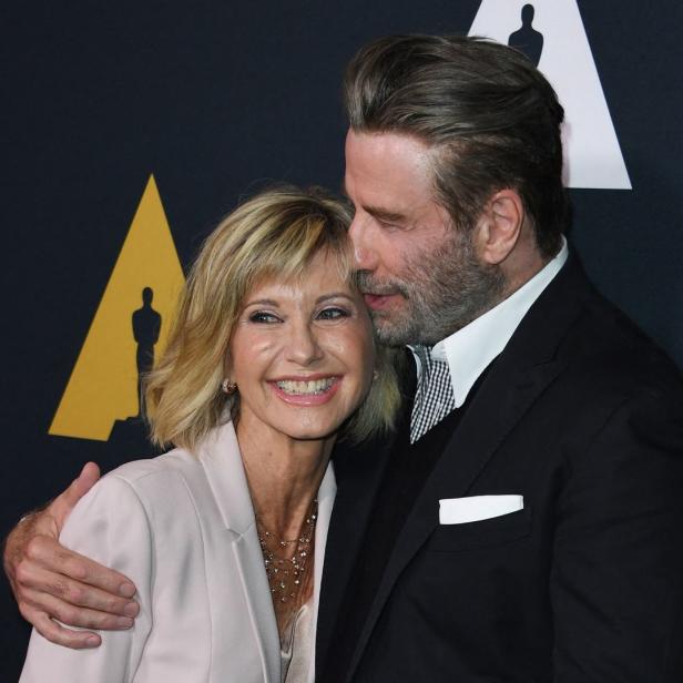 John Travolta umarmt Olivia Newton-John auf einer Veranstaltung.