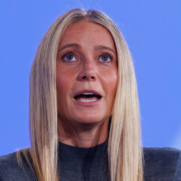 Gwyneth Paltrow spricht vor einem hellblauen Hintergrund.
