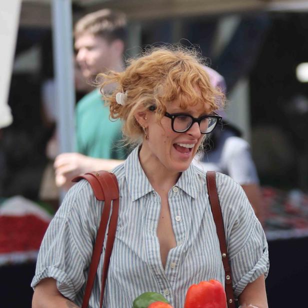 Eine Frau mit Brille kauft auf einem Markt Paprika.