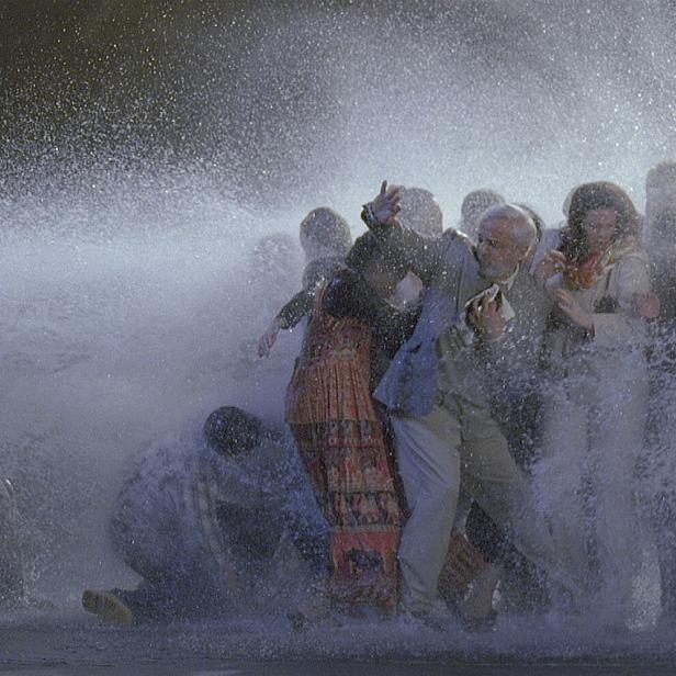 Eine Gruppe von Menschen wird von einem starken Wasserstrahl getroffen.